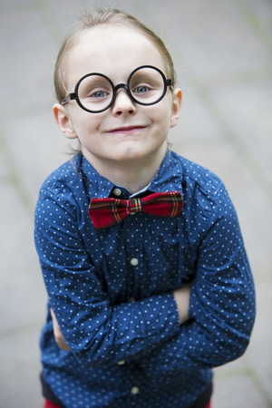 blond boy with bow tie and big glasses smiling at cameraの写真素材