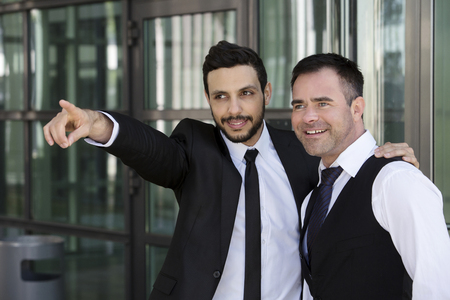 one handsome businessman is showing another something by pointingの写真素材