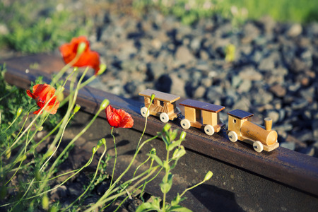 small wooden toy train on real railway tracks