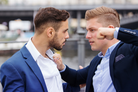 two young businessmen having a fight outsideの写真素材