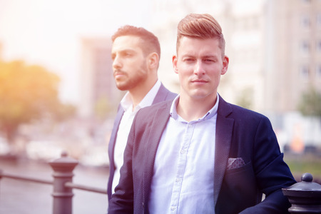 portrait of two handsome businessmen standing outside and waitingの写真素材