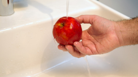 close up of hand washing a red apple in sinkの写真素材