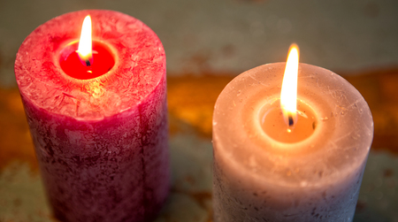close up of two burning candles on wooden tableの写真素材