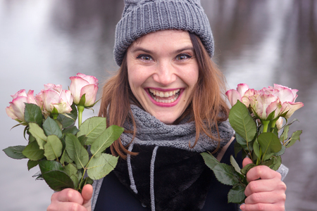 portrait of beautiful young woman outdoors with bouquet of pink rosesの写真素材