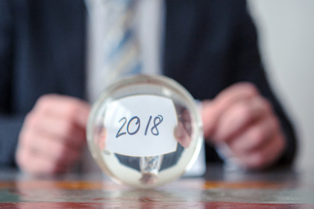closeup of man holding paper with the numbers 2018 in front of glass ballの写真素材