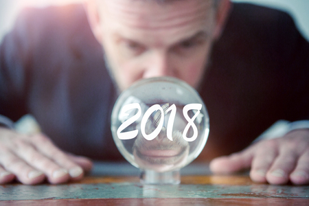 closeup of businessman looking at glass ball with the number 2018