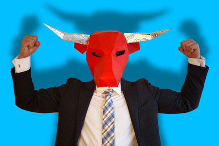 businessman with bull mask and blue background flexing his musclesの写真素材