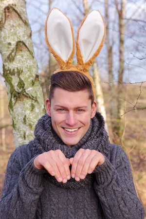 portrait of handsome blond man in the park with bunny earsの写真素材