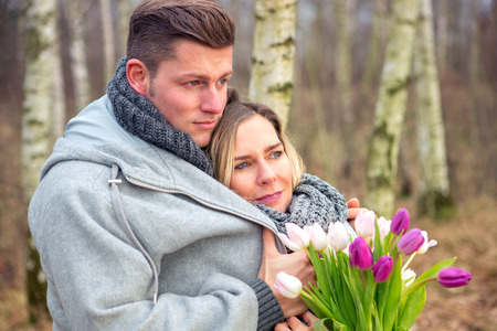 young couple outdoors with flowers embracing each otherの写真素材
