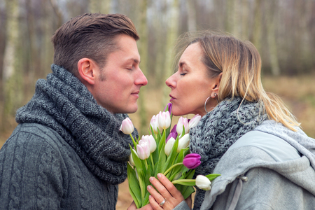 young couple outdoors with flowers embracing each otherの写真素材