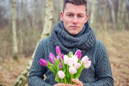 portrait of handsome blond man outdoors with tulipsの写真素材
