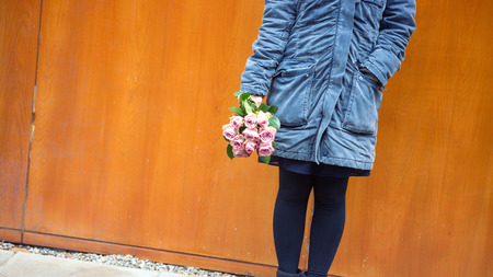 young woman standing outside in the cold with bouquet of rosesの写真素材