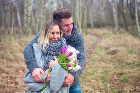young couple outdoors with flowers embracing each otherの写真素材