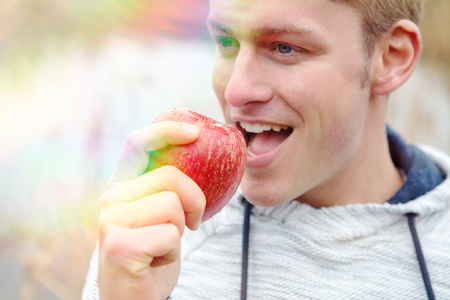 portrait of handsome man eating an red appleの写真素材