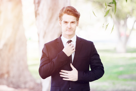 portrait of handsome man in a suit standing in parkの写真素材