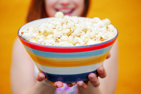 closeup of young woman holding a bowl of popcornの写真素材