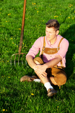 handsome blond bavarian man sitting in the grassの写真素材