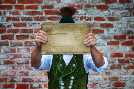 bavarian man outdoors holding a wooden plank in front of his headの写真素材