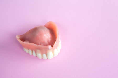 closeup of dental prosthesis on a pink background