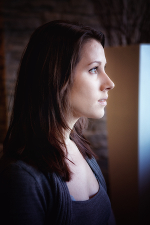 portrait of brunette young woman looking out of windowの写真素材