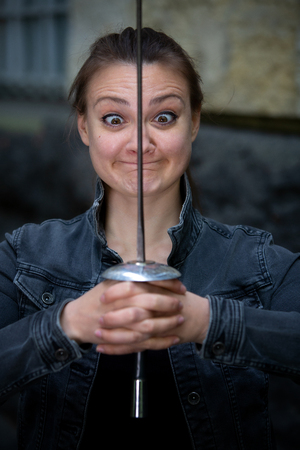 portrait of young brunette cross-eyed woman outdoors with epee