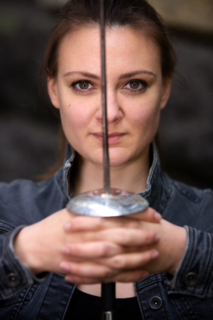 portrait of young brunette woman outdoors with epee