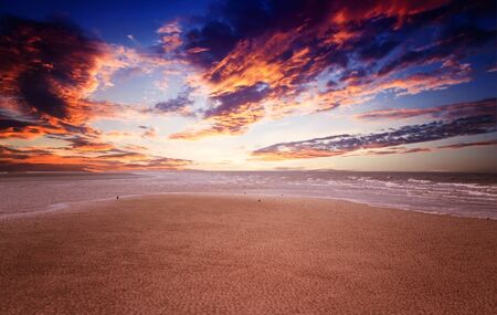 colorful sandy beach at sunset with cloudsの写真素材