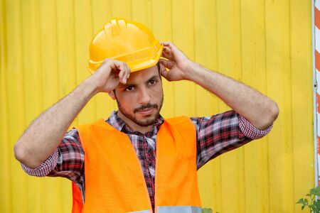 Handsome construction worker wearing yellow helmet and orange vestの写真素材
