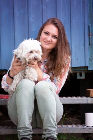 portrait of young brunette woman sitting outdoors with her little dog