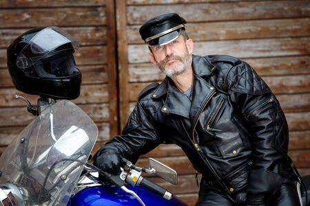 portrait of sexy biker dressed in black leather sitting on his bikeの写真素材