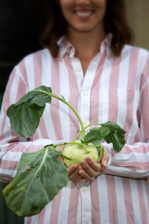 portrait of young brunette woman holding a turnip cabbageの写真素材