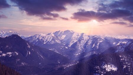 panoramic view of snowy mountains and rays of the sun