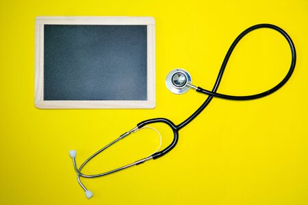 close-up of blackboard and stetoscope on yellow backgroundの写真素材