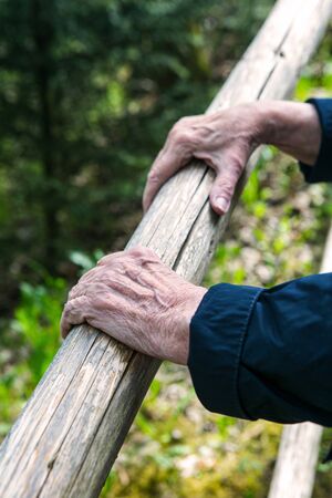 close-up of old womans hands resting at a railing in natureの写真素材