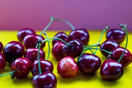 close-up of red delicious cherries on a yellow tableの写真素材