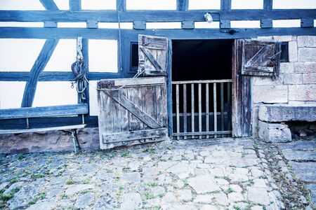 an old wooden rustic vintage barn door with cobblestones in front of itの写真素材