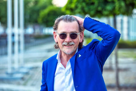 portrait of handsome businessman in his 50s with sunglasses standing outside