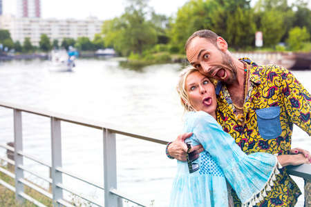 young couple by a river hugging each other and making funny faces