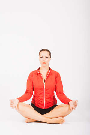 blond woman in sportswear sitting in lotus position in studioの写真素材