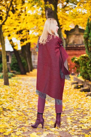 backside of blond woman standing outdoors in a park in autumnの写真素材
