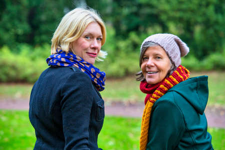 portrait of two women in their 50s standing in park in autumnの写真素材