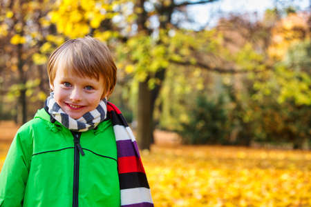 portrait of smiling young boy standing in park in autumnの写真素材