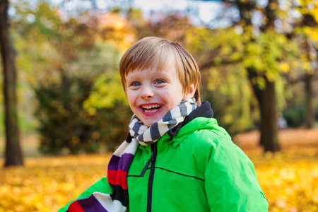 portrait of smiling young boy standing in park in autumnの写真素材