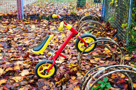 Close-up of kids tricycle outside at bicycle stand in autumnの写真素材
