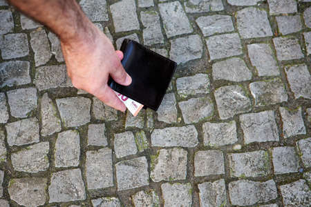 close-up of leather wallet lying on street and a hand grabbing itの写真素材