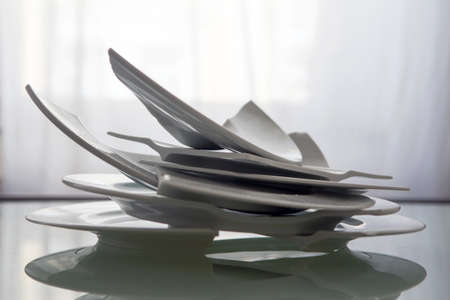 Pile of broken white plates on a glass tableの写真素材