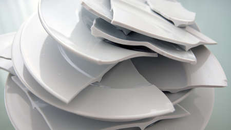 Pile of broken white plates on a glass tableの写真素材