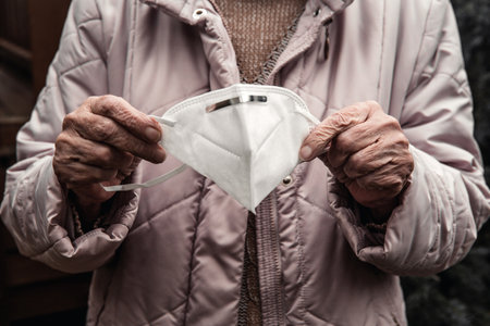 close-up of older womans hands holding face maskの写真素材