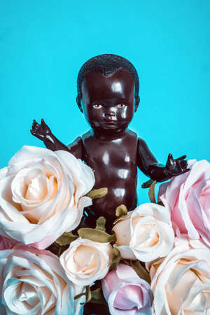 black doll with bouquet of flowers on a blue backgroundの写真素材