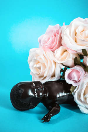 black doll with bouquet of flowers on a blue backgroundの写真素材